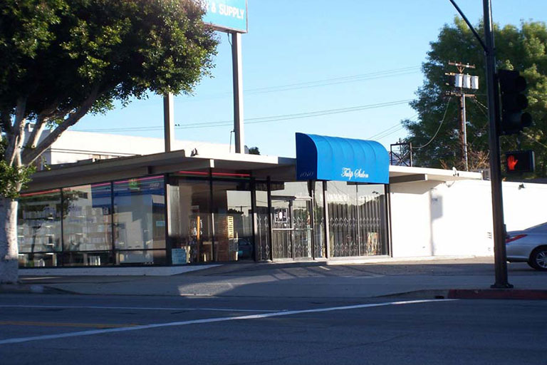Storefront with blue awning on street corner.