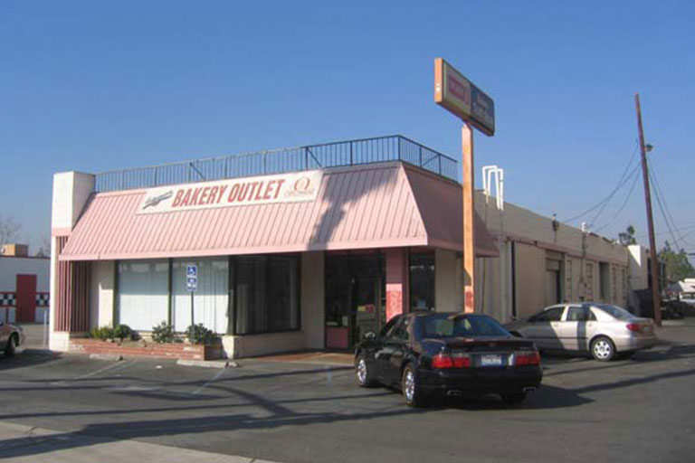 Bakery outlet with parked cars outside.