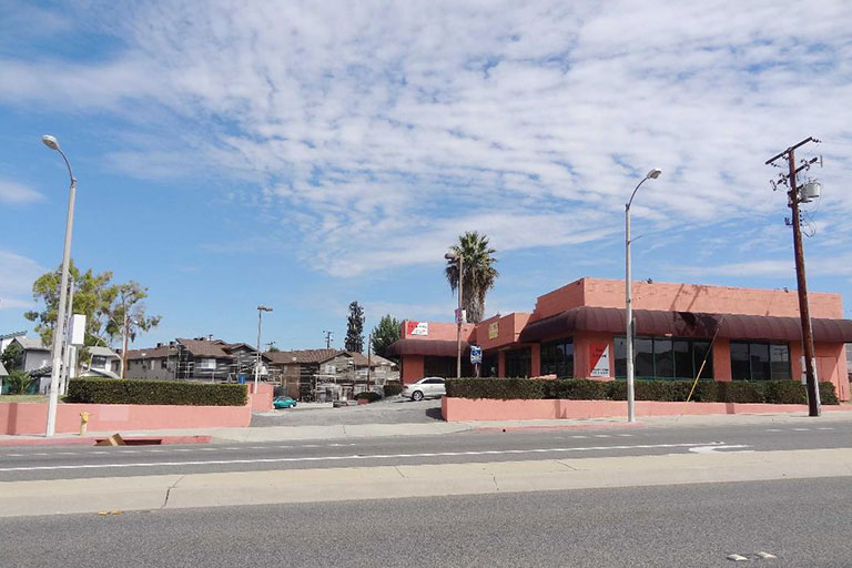 Red building with palm tree and road.