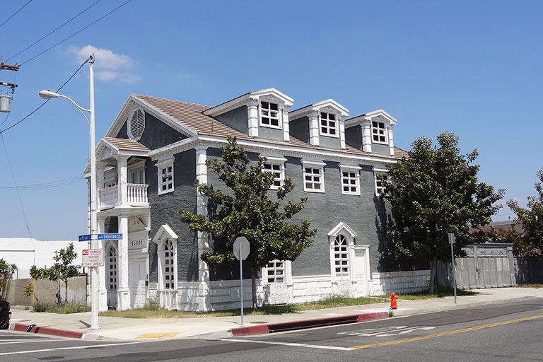 Gray building on a sunny street corner.