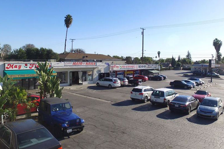 Shopping plaza with parked cars and stores.