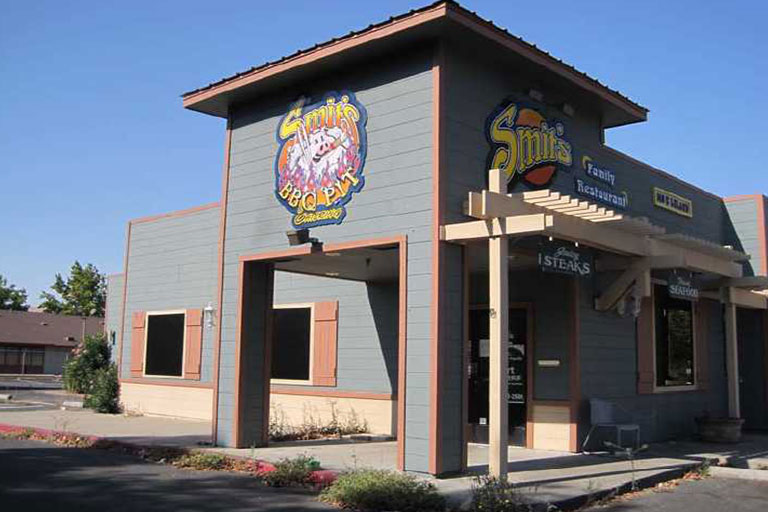 Gray building with colorful restaurant signs outside.