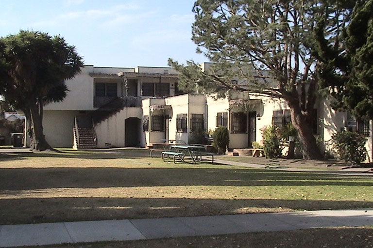 White building with trees and picnic table.