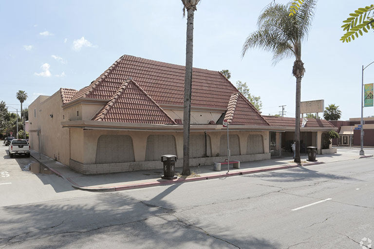 Closed restaurant with red roof and palm trees.