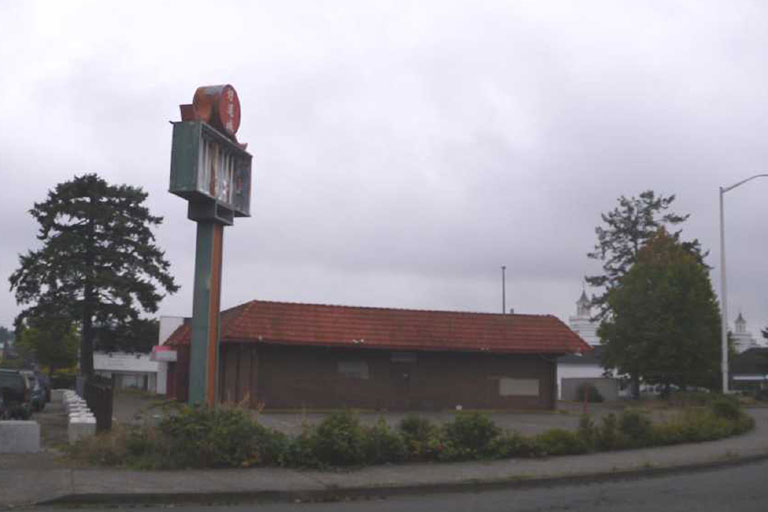 Abandoned building with empty sign and trees.