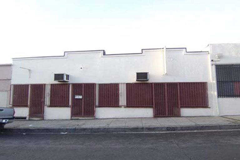 White building with boarded windows and AC units.