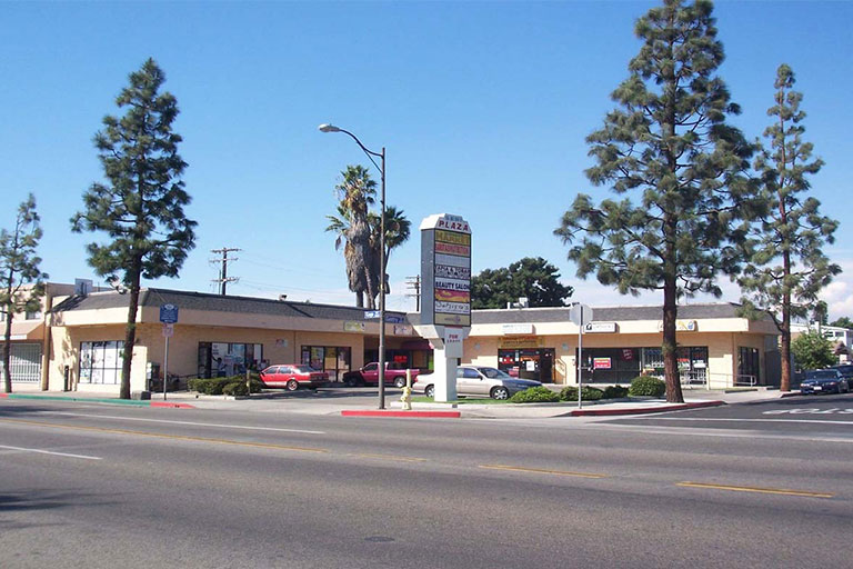 Shopping center with trees and parked cars.