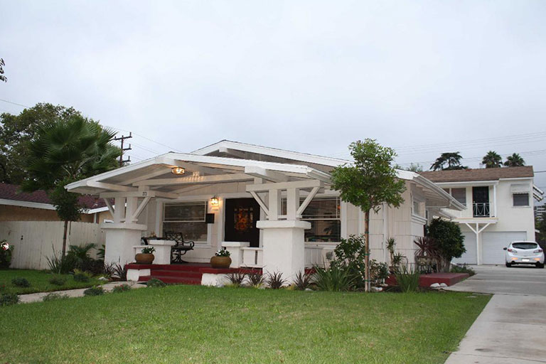 White house with porch and green lawn.