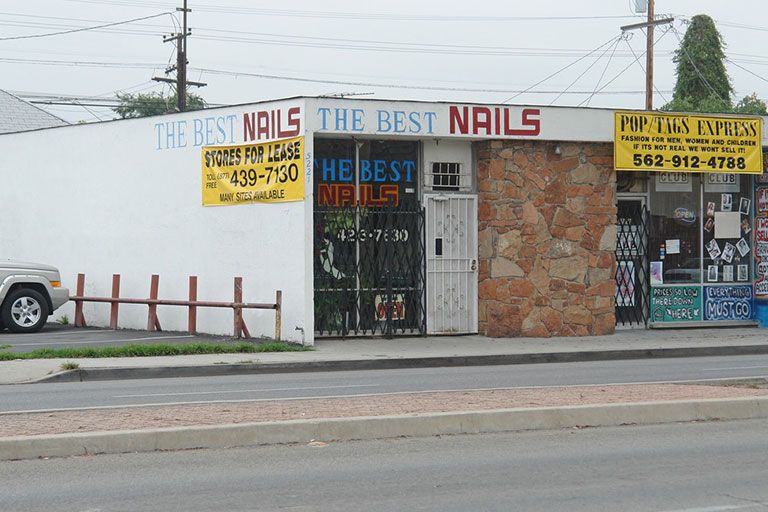 Nail salon storefront with lease signs.