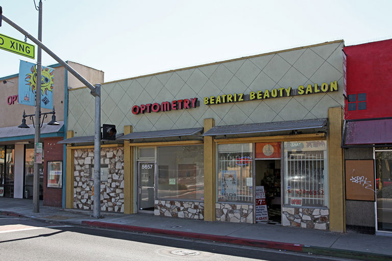 Optometry and beauty salon storefronts on street.