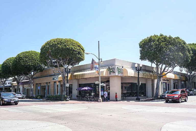 Street corner with shops and parked cars.