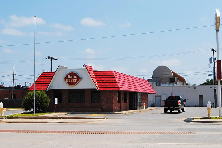 Red-roofed fast food restaurant with parking lot.
