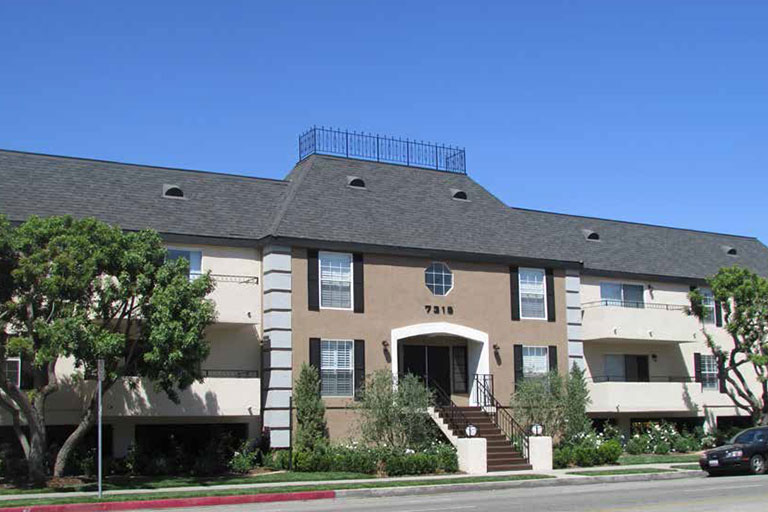 Two-story apartment building with landscaped entrance.