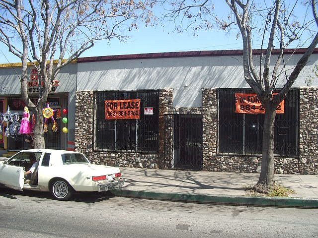 Stone building with "For Lease" signs, car parked.