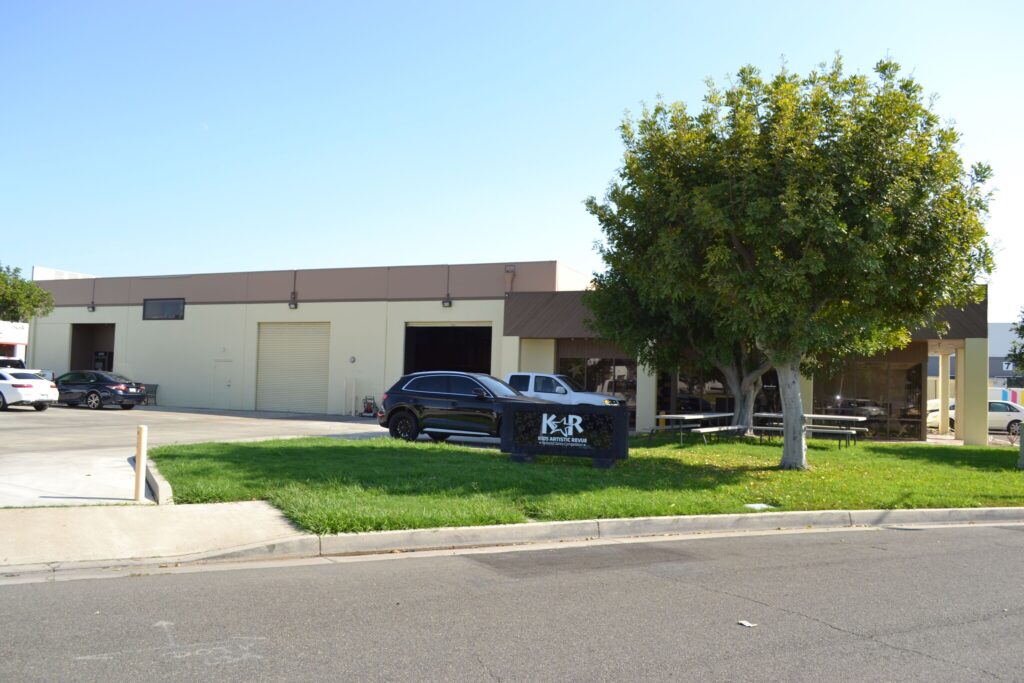 Industrial building with parked cars and tree.