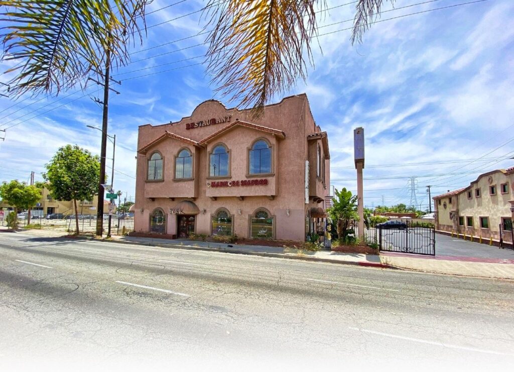 Pink building with palm trees and sign.